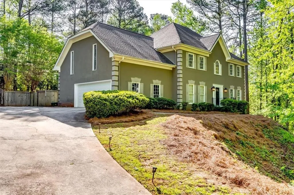 View of front of home with roof with shingles, an attached garage, stucco siding, and driveway