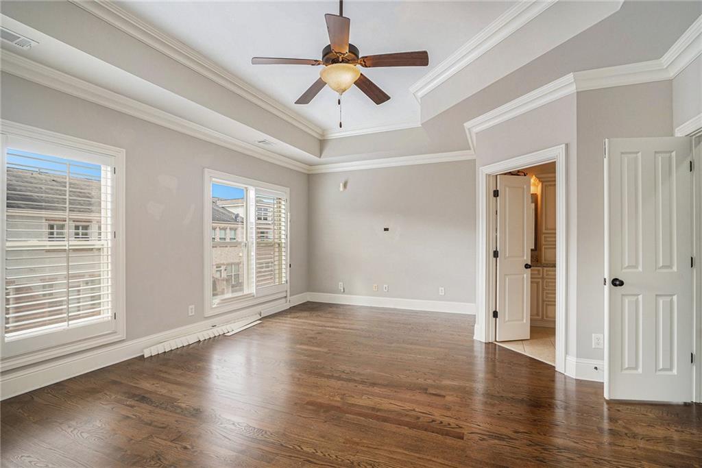 Spare room with ornamental molding, dark hardwood / wood-style flooring, a tray ceiling, and ceiling fan