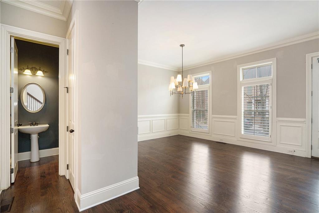 Empty room featuring an inviting chandelier, dark hardwood / wood-style floors, and ornamental molding