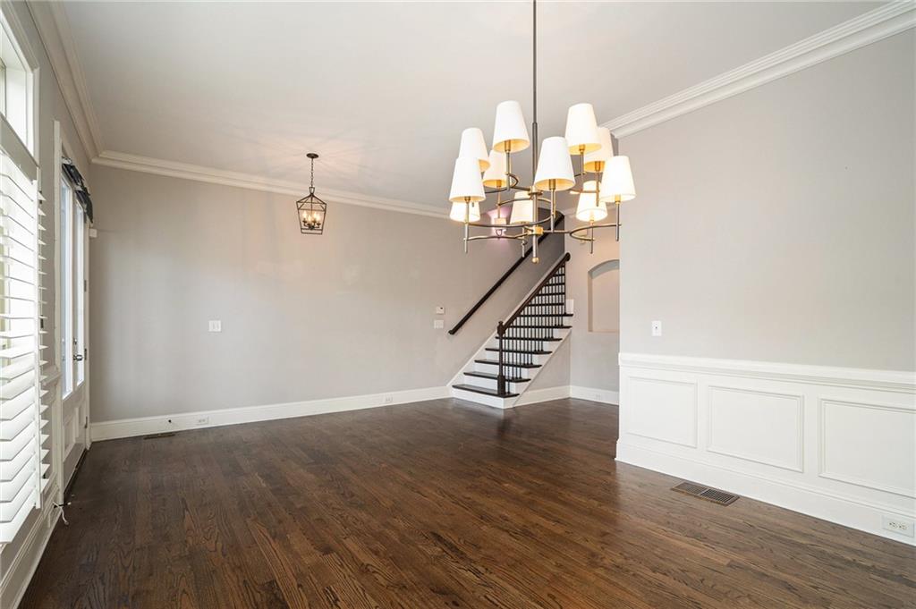 Empty room with an inviting chandelier, dark hardwood / wood-style floors, and a healthy amount of sunlight