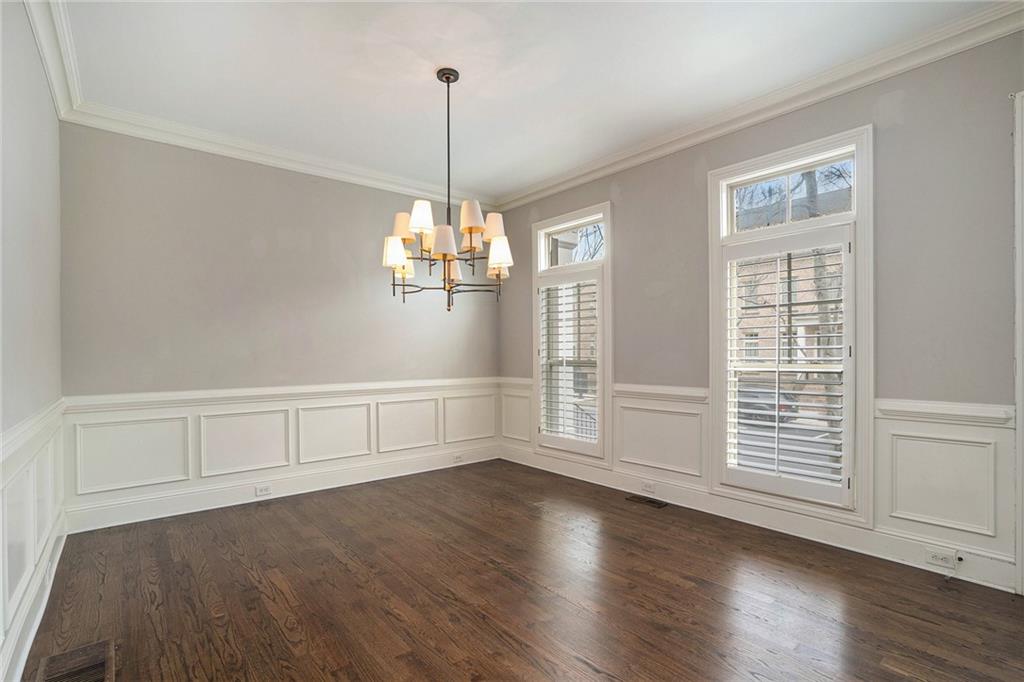 Spare room featuring dark hardwood / wood-style floors, a notable chandelier, and crown molding