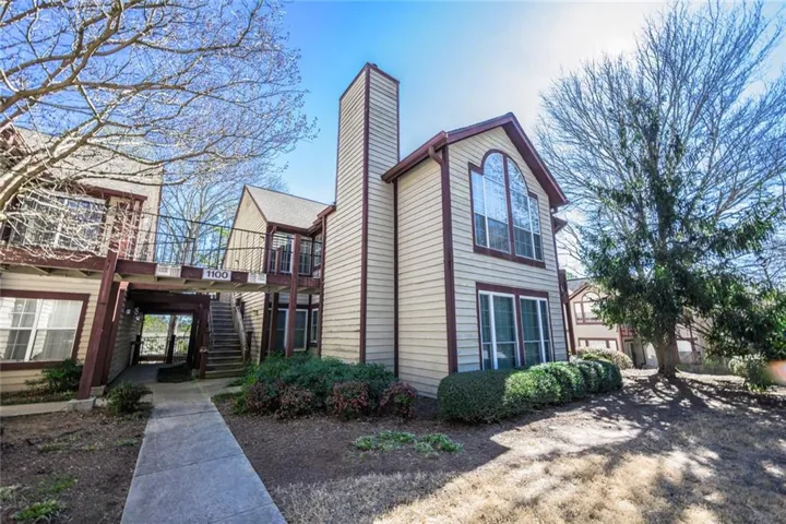 Exterior featuring beige siding, dark trim, and a prominent arched window