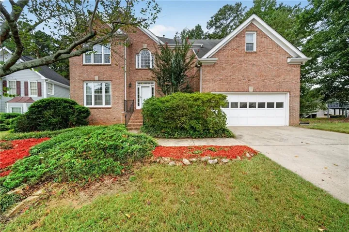 Brick facade with multiple windows, arched window detail, and a two-car garage