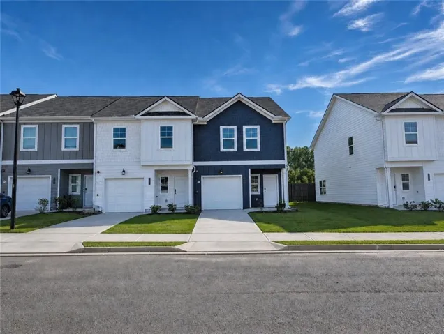 Modern townhomes featuring varied exterior siding, attached garages, and paved driveways