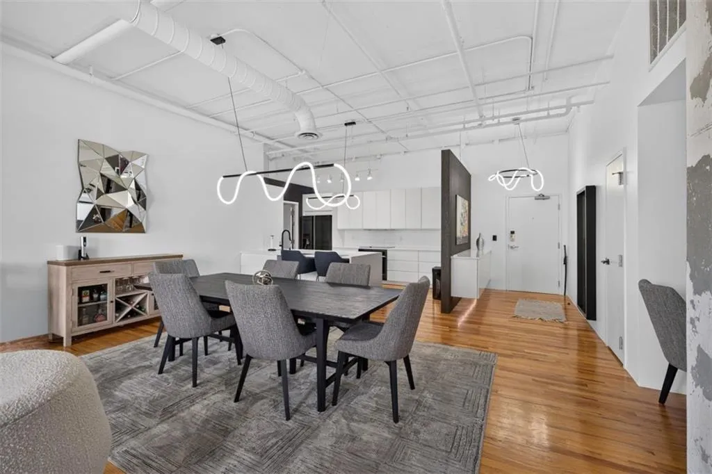 Open-concept living space featuring wood-finish flooring, exposed ductwork, and white walls