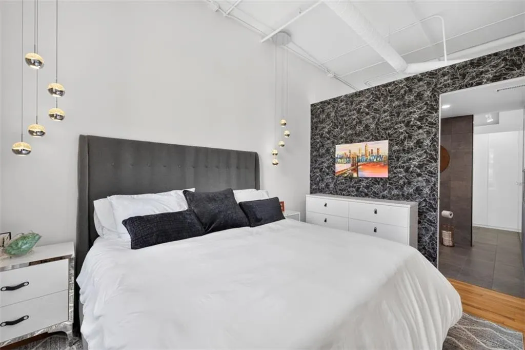Accent wall with dark patterned finish, exposed ceiling ductwork, and suspended pendant lighting