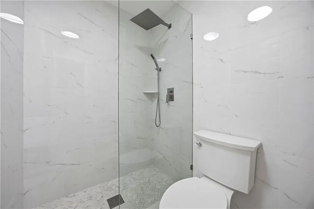 Bathroom featuring toilet and a marble finish shower