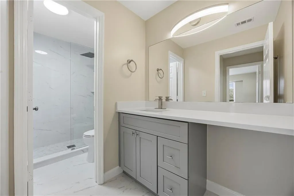 Bathroom with vanity, light marble finish flooring, and a marble finish shower