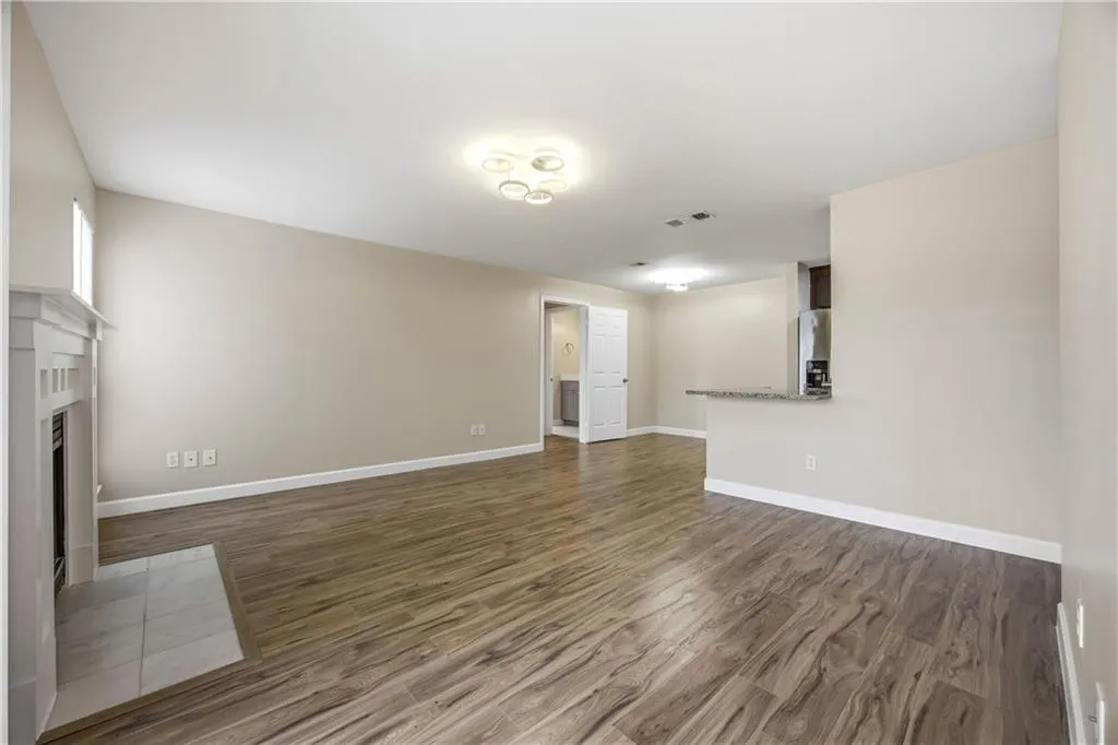 Unfurnished living room with dark wood-type flooring and a fireplace with flush hearth