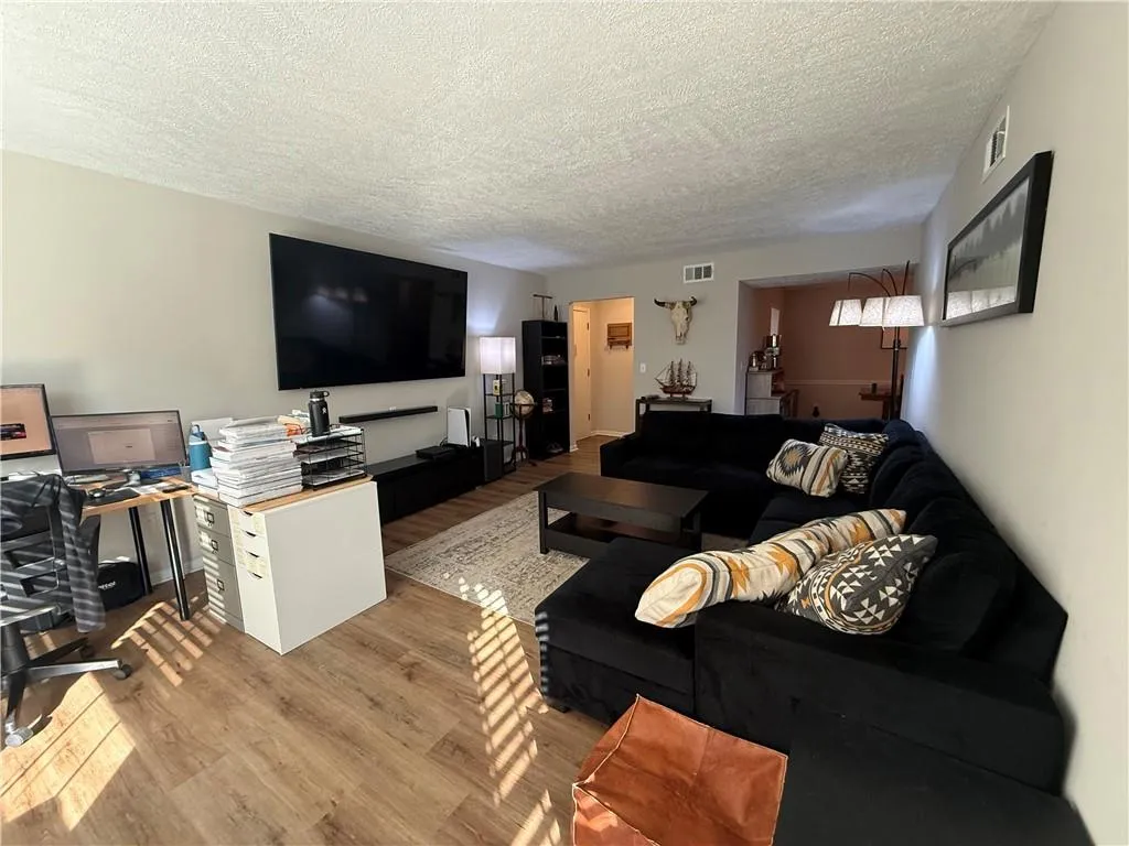 Living area with wood finished floors, a desk, and a textured ceiling