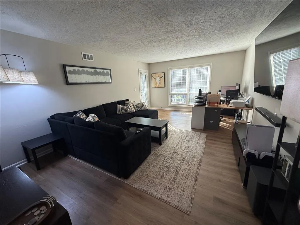 Living room with an office area, dark wood finished floors, and a textured ceiling
