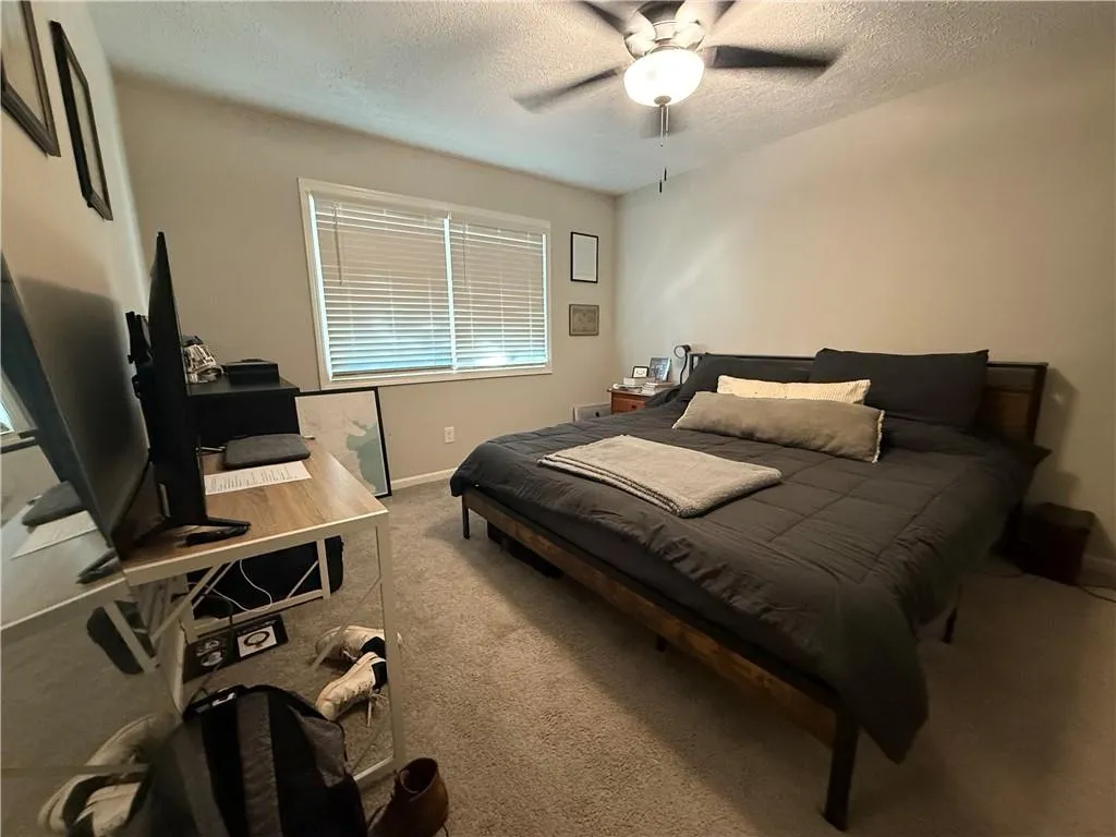 Carpeted bedroom featuring a textured ceiling and a ceiling fan