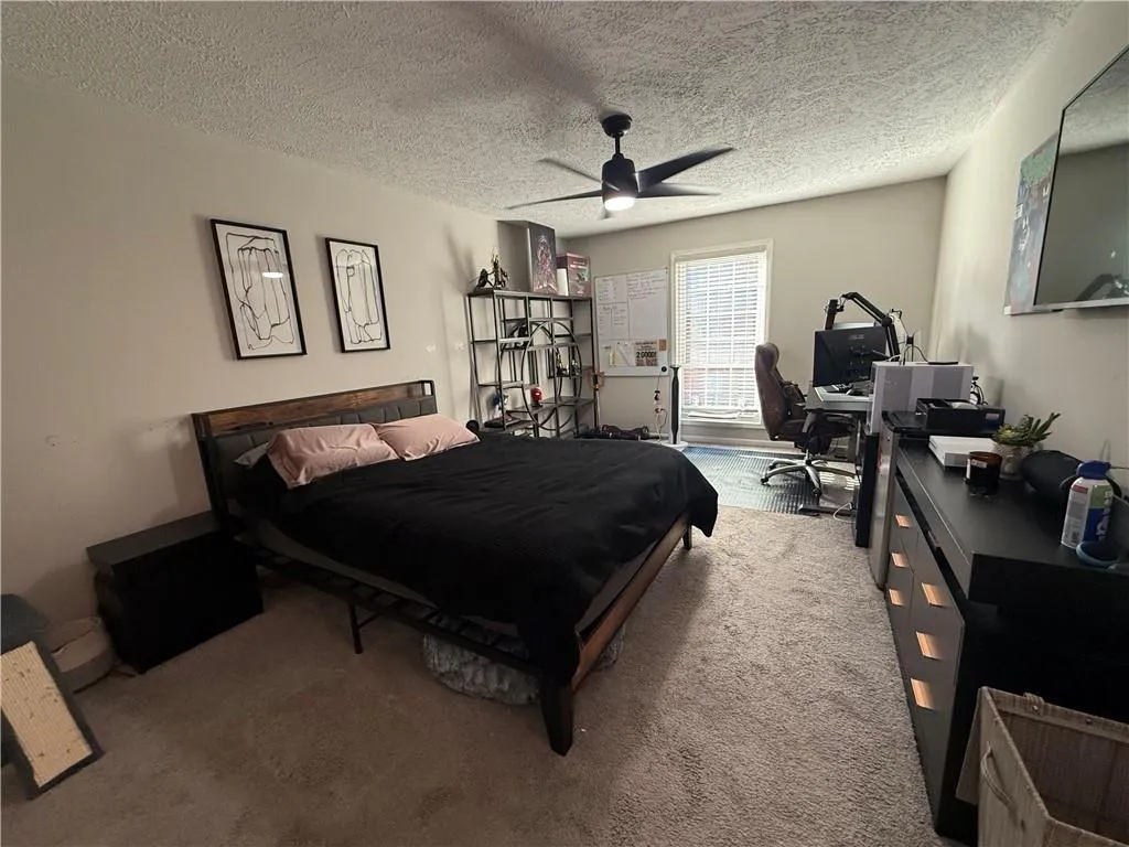 Carpeted bedroom featuring a desk, a textured ceiling, and ceiling fan