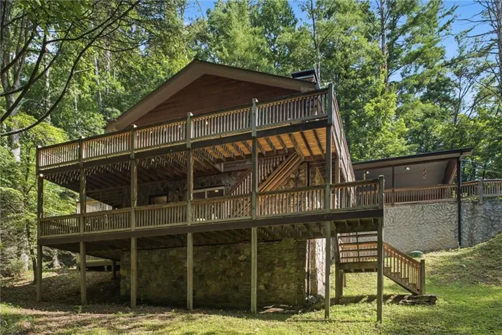 Multi-level wooden decks surround this stone-clad residence, featuring extensive outdoor living space
