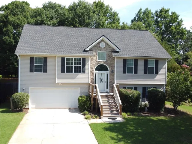 Light-toned siding exterior featuring a stone accent façade, dark shutters, and a prominent front entry with an arched transom window