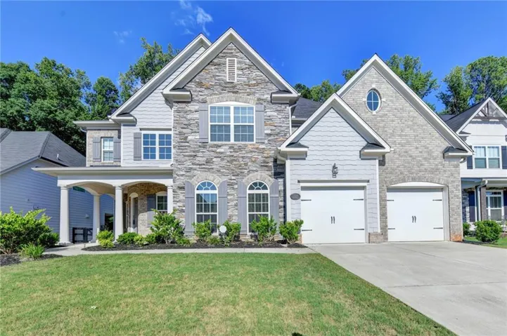 Stone and siding exterior with a covered entry, arched windows, and an attached two-car garage