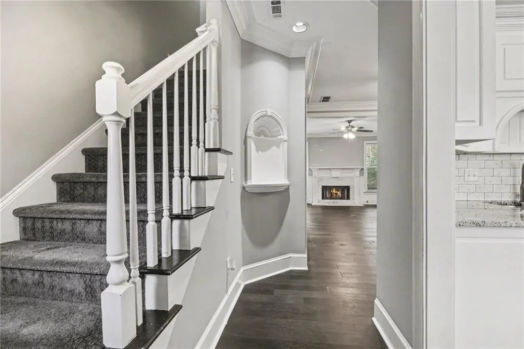 Staircase with a high end fireplace, crown molding, wood finished floors, recessed lighting, and ceiling fan