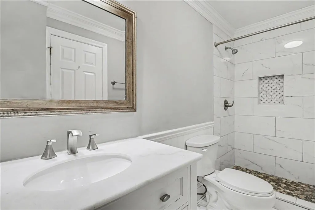 Bathroom with ornamental molding, vanity, a stall shower, and wainscoting