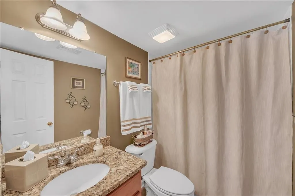Bathroom featuring vanity, toilet, and a shower wi
