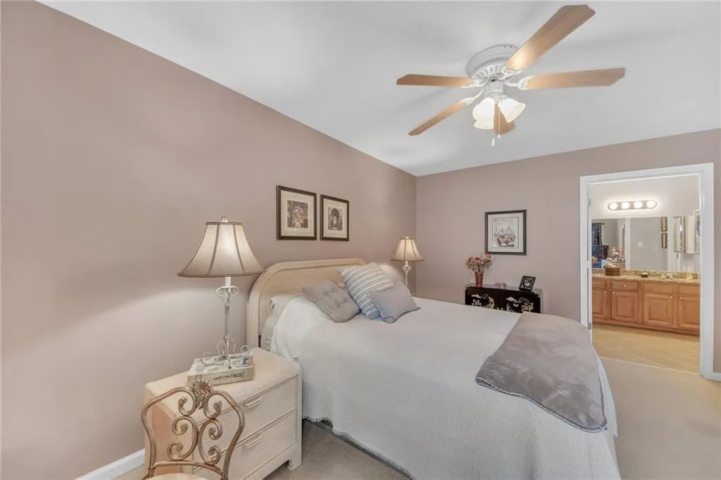 Bedroom with connected bathroom, light carpet, and