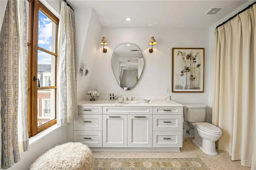 White vanity with undermount sink, a stone-finish countertop, and dark hardware
