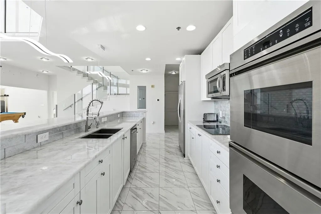 Kitchen featuring appliances with stainless steel finishes, white cabinets, billiards table, light stone countertops, and light marble finish floors