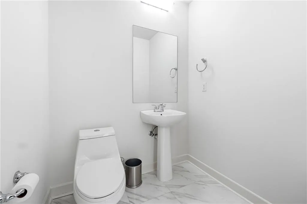 Half bath with light marble finish floors and baseboards