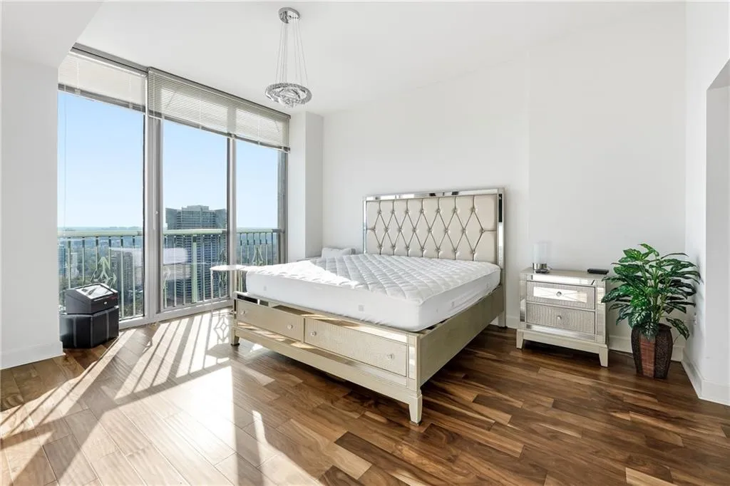 Bedroom featuring floor to ceiling windows, wood finished floors, and access to exterior