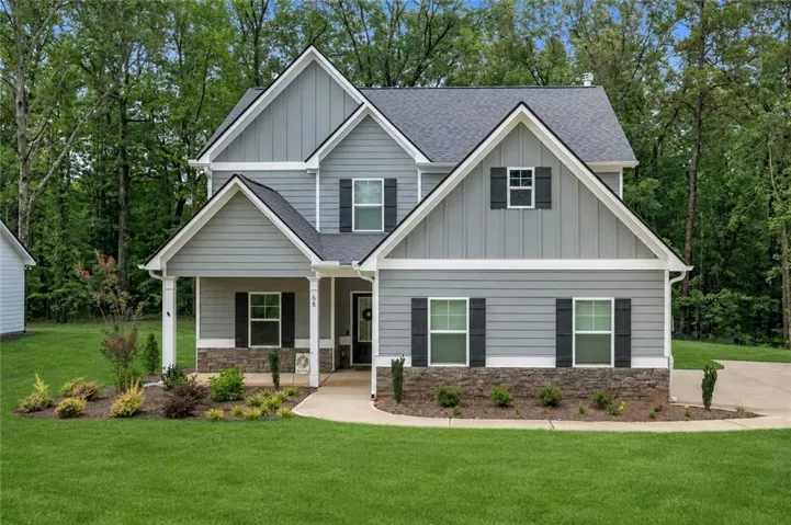 Front Exterior – A full front view highlights the home’s Craftsman-inspired design, covered porch, decorative shutters, and wooded backdrop.