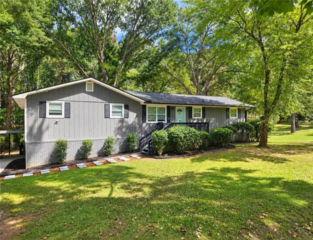 Gray siding exterior with a light brick foundation, black shutters, white trim, and an attached carport