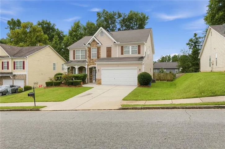 Two-story exterior with stone and siding accents, front porch, attached garage, and a concrete driveway