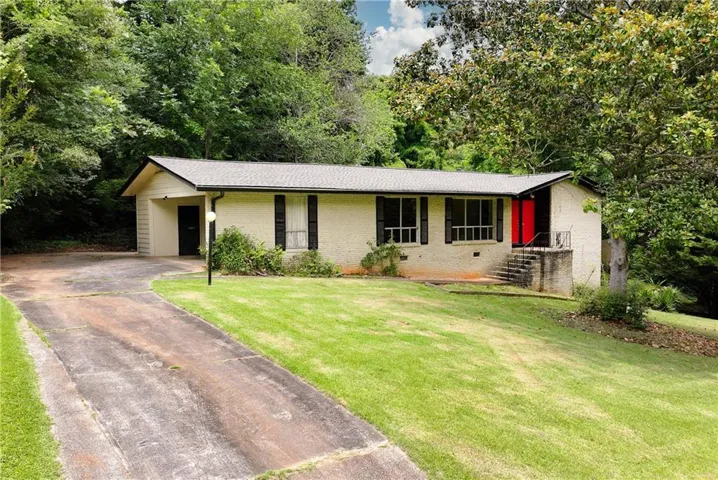 Single-story residence featuring a red entry door, white brick exterior, and dark shutters