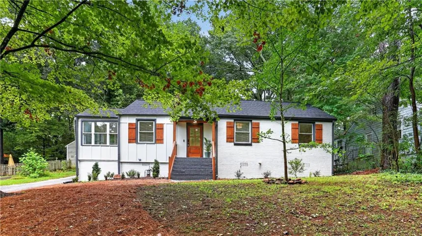 White painted brick exterior with dark shingle roof and wood-tone shutters