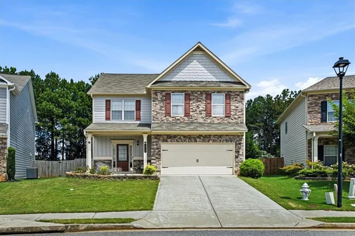 Two-story residence featuring a stone and siding exterior, an attached two-car garage, and a concrete driveway