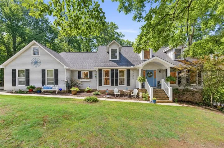 Light gray siding home featuring multiple dormer windows and a covered front porch with white railings