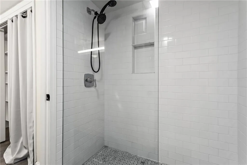 Shower enclosure featuring subway tile walls, a built-in niche, and pebble-style floor tiling