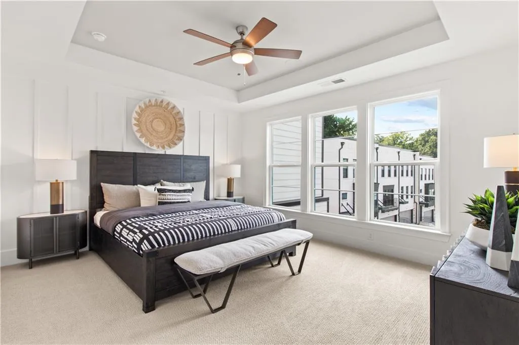 Bedroom with a tray ceiling, light colored carpet, and ceiling fan