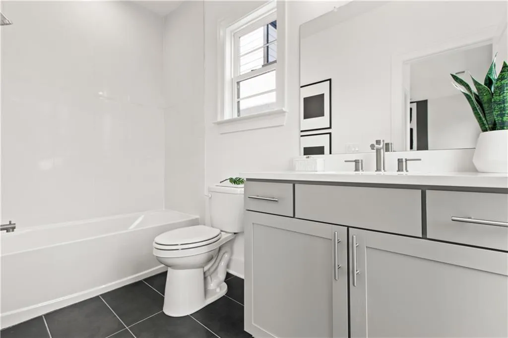 Bathroom featuring dark tile patterned flooring, vanity, and bathtub / shower combination