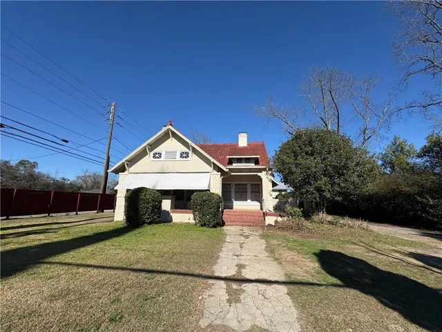 Cream-colored exterior with a red tile roof and a covered front porch featuring brick stairs