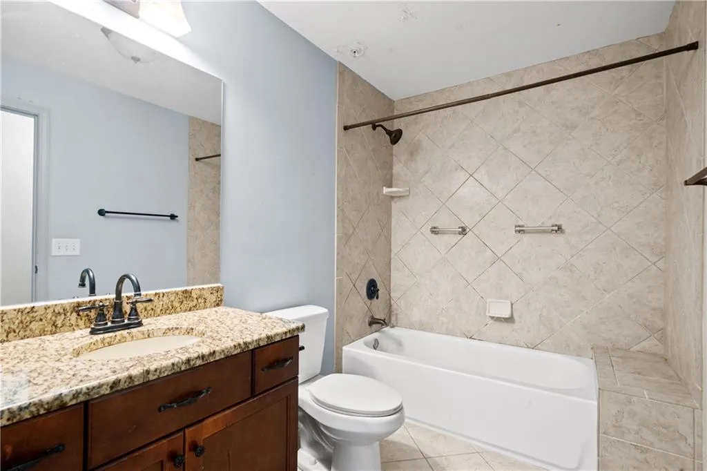 Full bathroom featuring tiled shower / bath, vanity, toilet, and tile patterned flooring