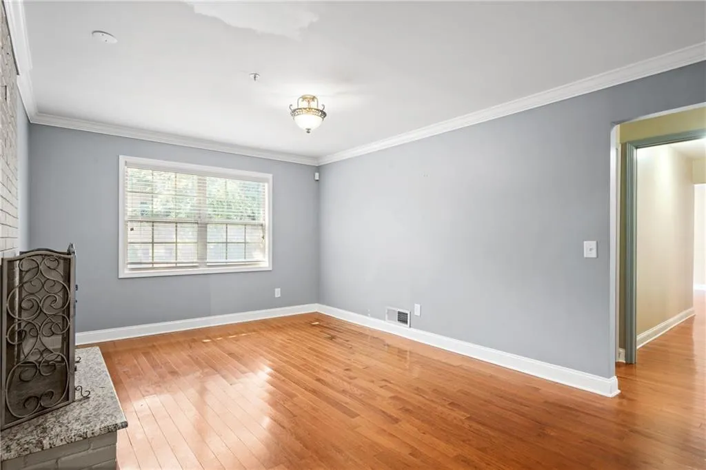 Empty room featuring ornamental molding and light wood-type flooring