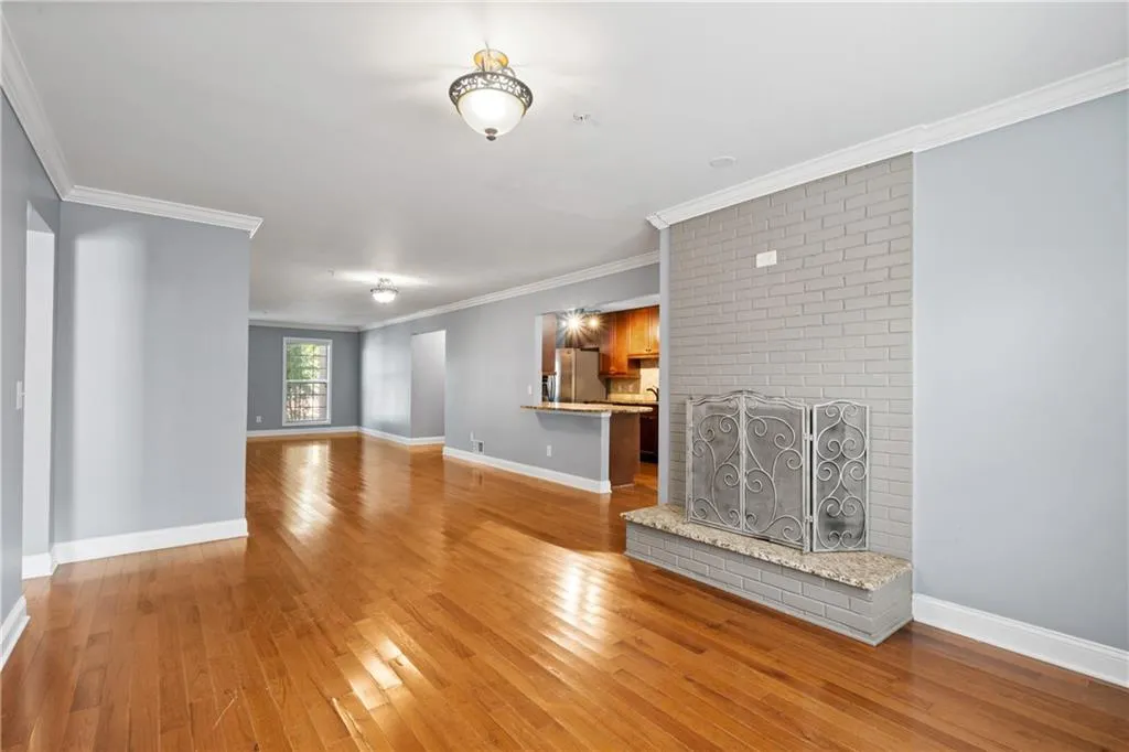 Unfurnished living room featuring light hardwood / wood-style floors, crown molding, and a brick fireplace