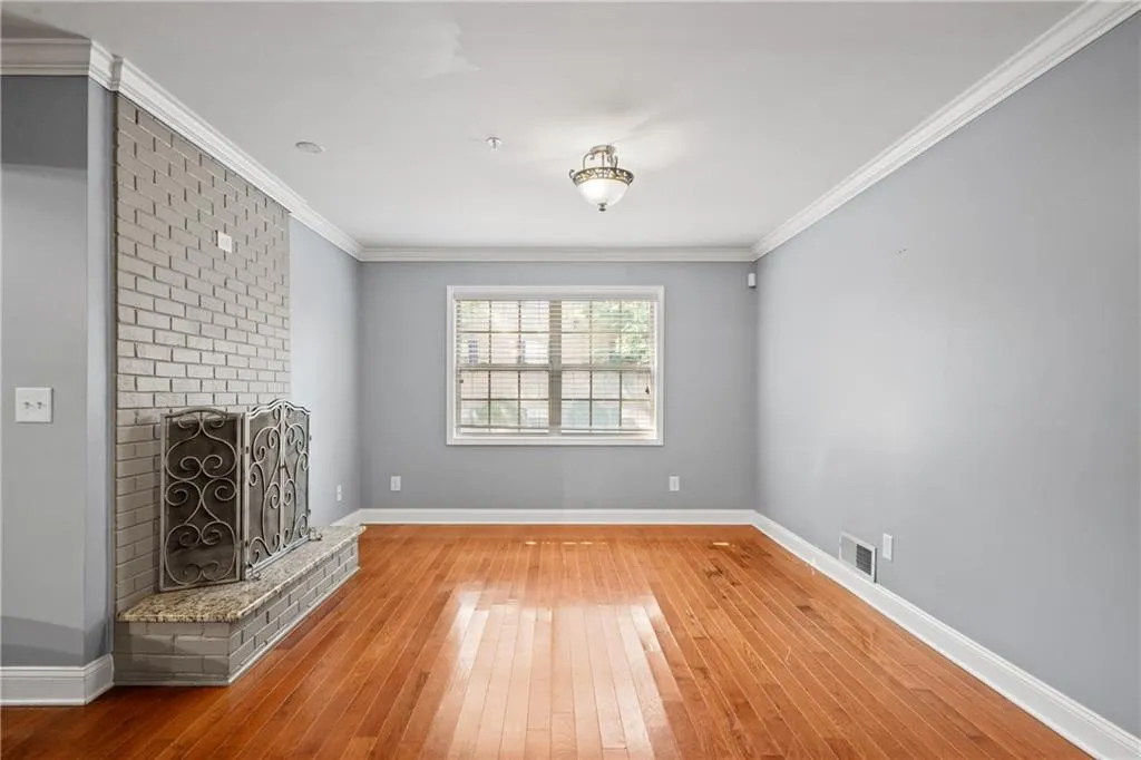 Unfurnished living room with crown molding, hardwood / wood-style floors, and a fireplace