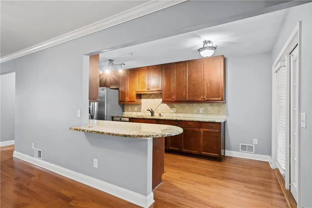 Kitchen featuring light wood-type flooring, stainless steel refrigerator, tasteful backsplash, light stone counters, and sink