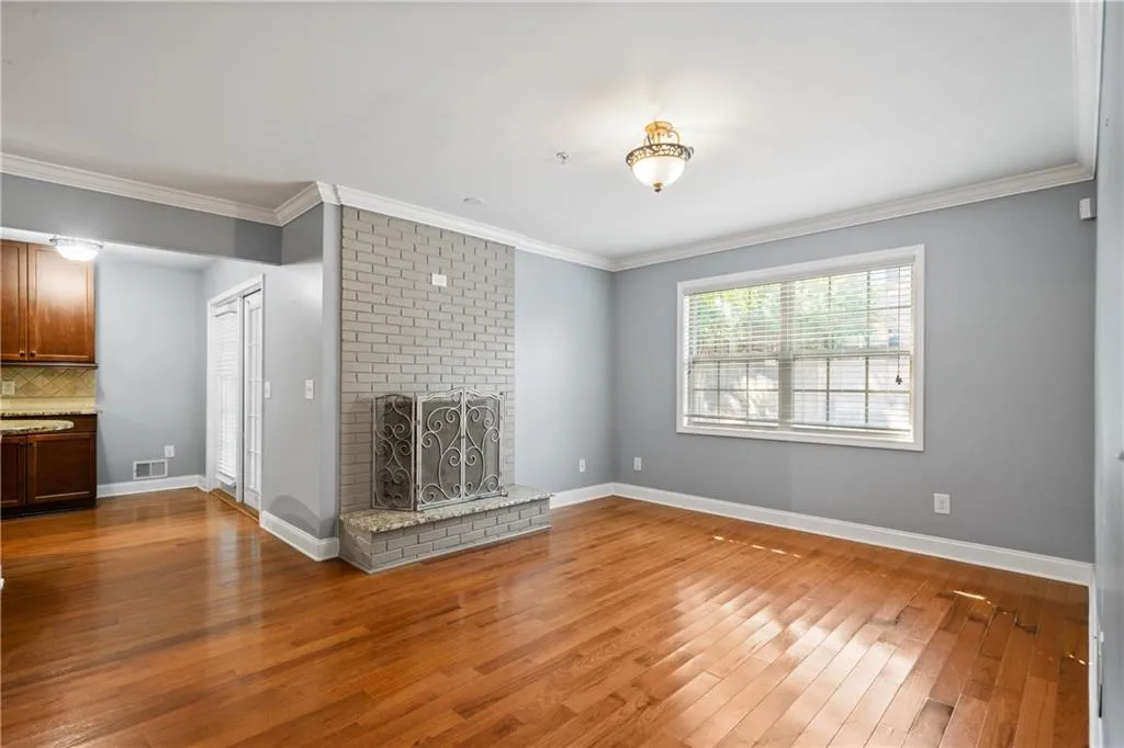 Unfurnished living room featuring a fireplace, ornamental molding, and hardwood / wood-style flooring