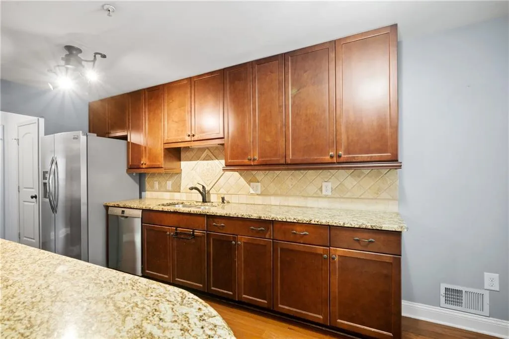 Kitchen featuring light stone counters, stainless steel appliances, light hardwood / wood-style floors, and sink
