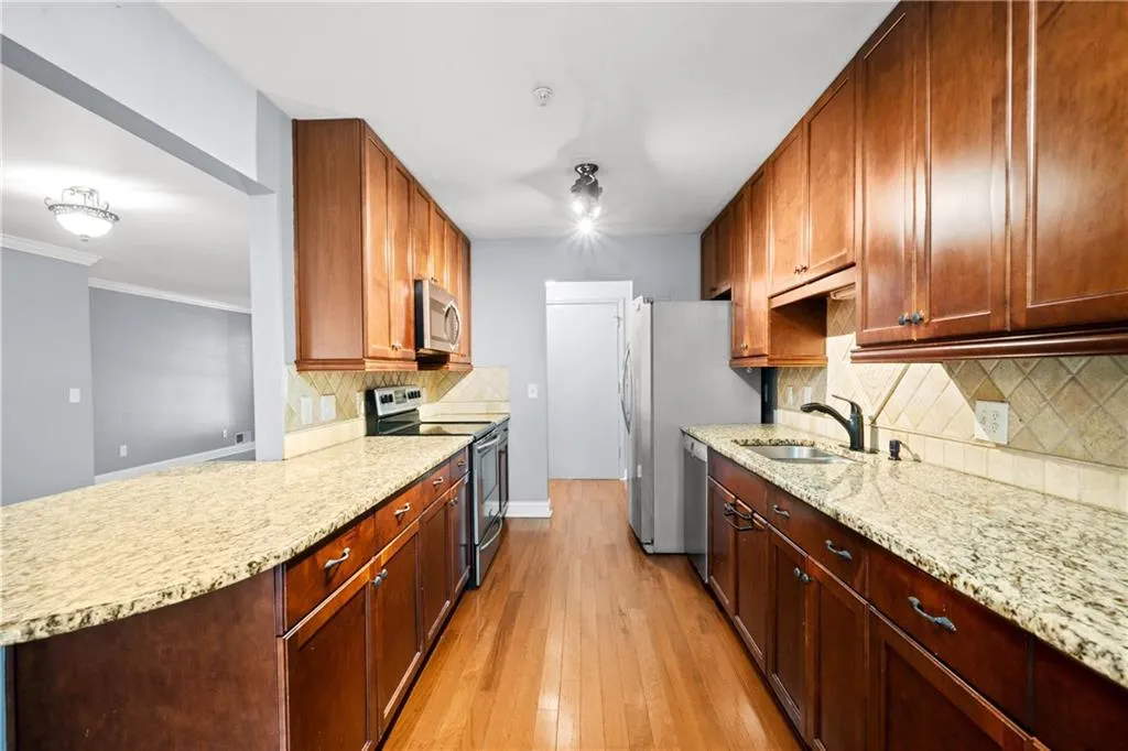 Kitchen featuring stainless steel appliances, sink, light wood-type flooring, and tasteful backsplash