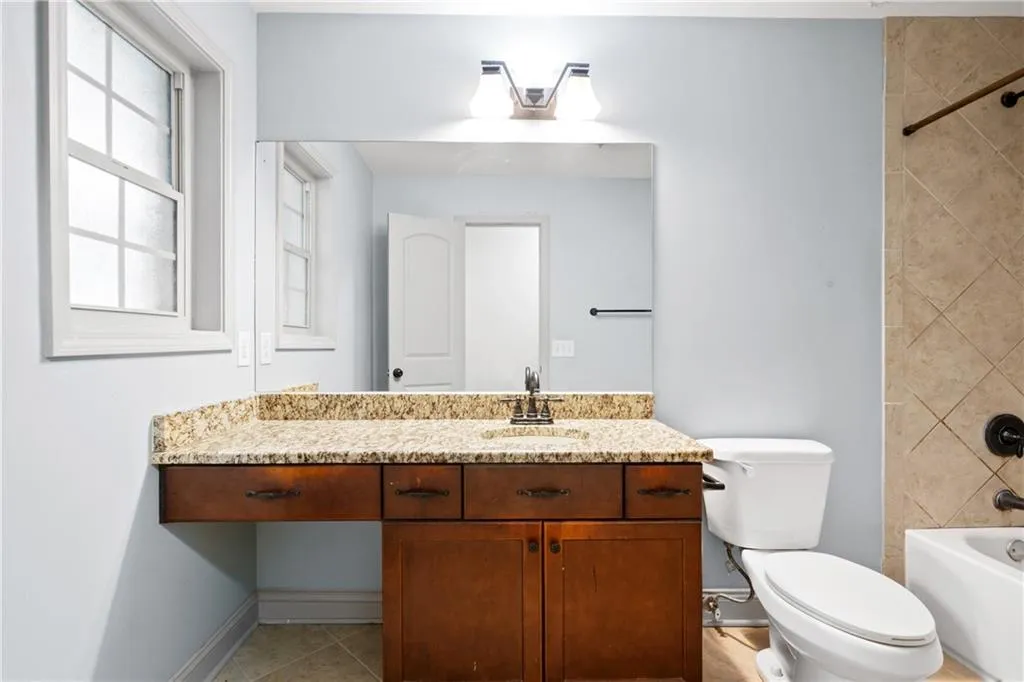 Full bathroom with a healthy amount of sunlight, toilet, vanity, and tiled shower / bath