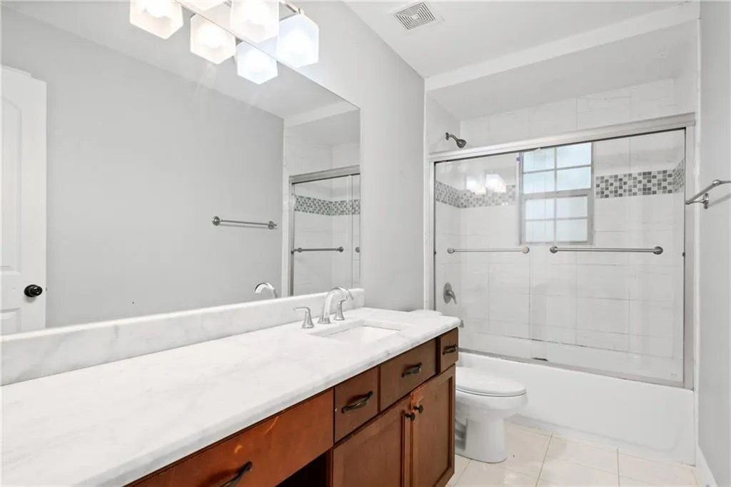 Full bathroom featuring vanity, toilet, bath / shower combo with glass door, and tile patterned floors