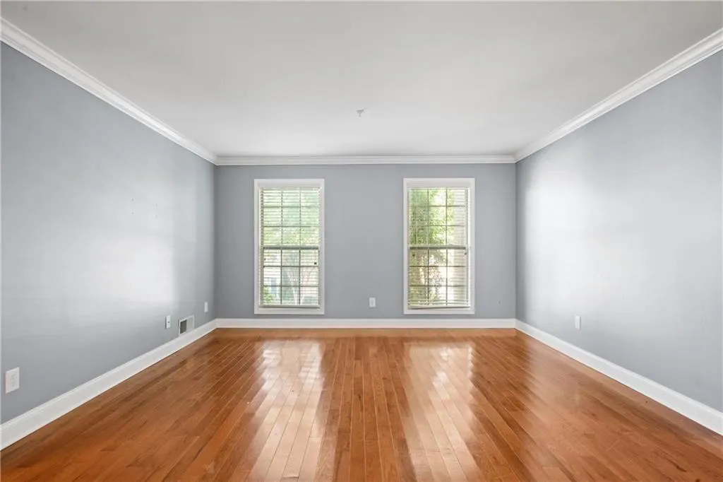 Spare room with ornamental molding, a wealth of natural light, and light hardwood / wood-style flooring